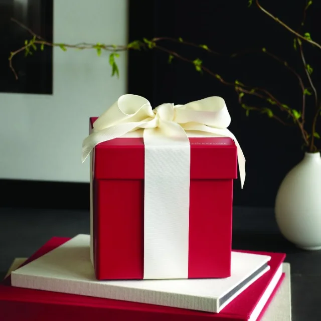 A closed red gift box tied with a cream ribbon bow